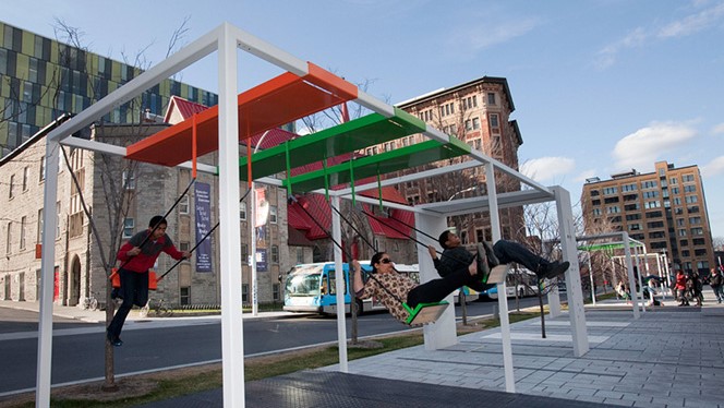 People swing on playground swings as a part of the 21 Swings Installation in 
                        Montreal, Quebec, Canada